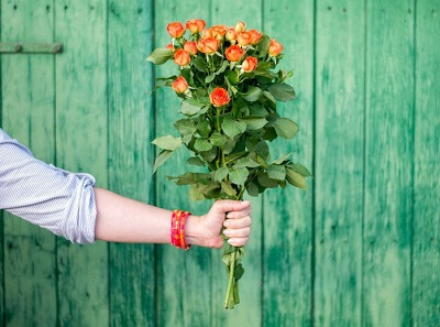 Hand holds out a bouquet of orange flowers.